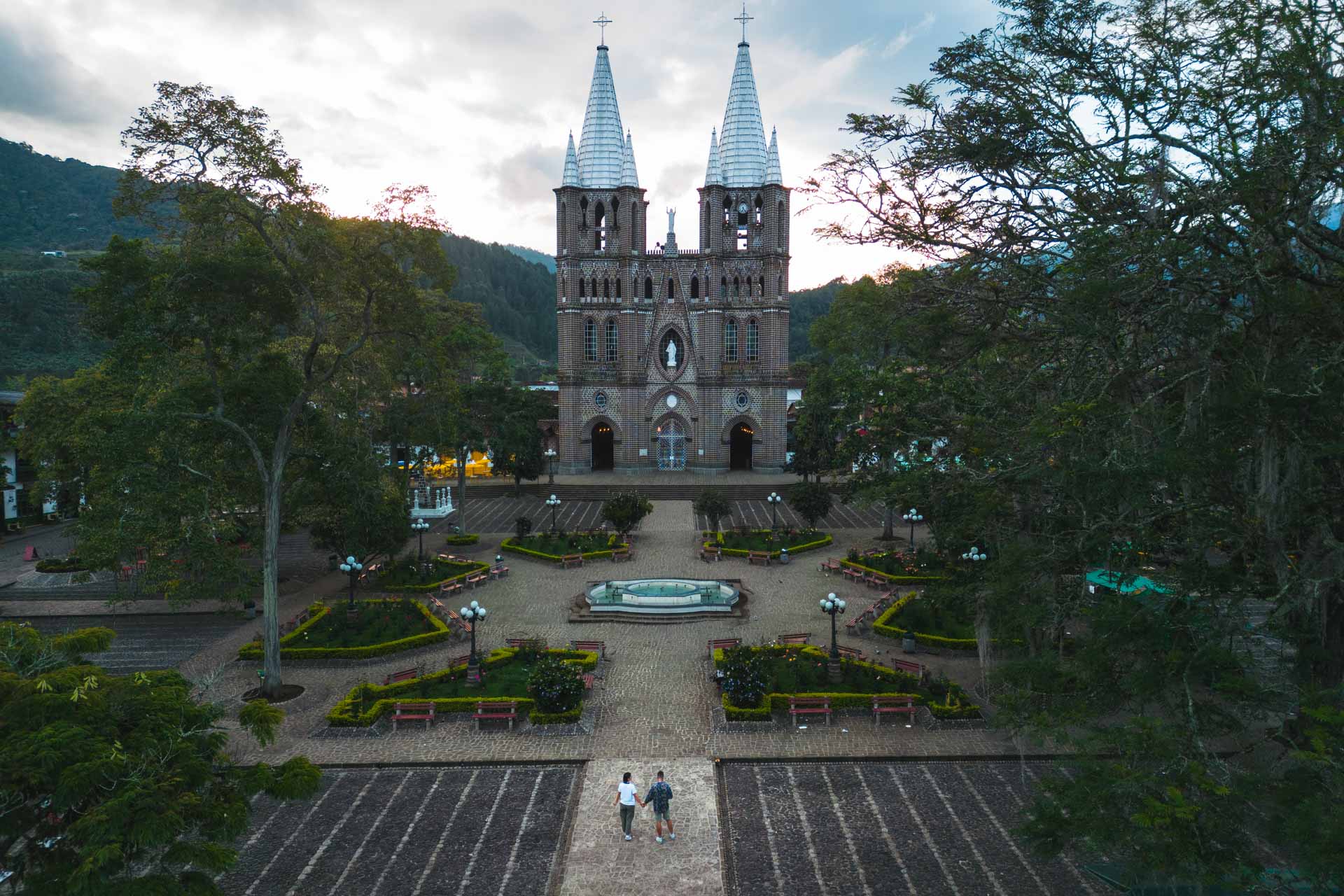 A view of the Basilica of Immaculate Conception in Jardin, Colombia, framed by trees.
