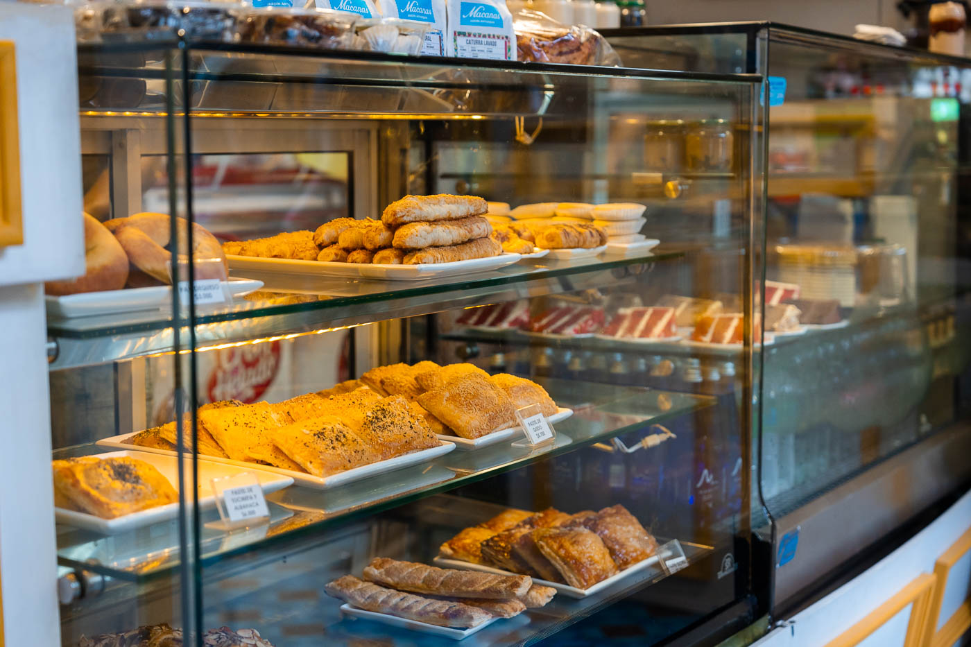 Trays of baked goods on glass shelves inside Cafe Macanas.