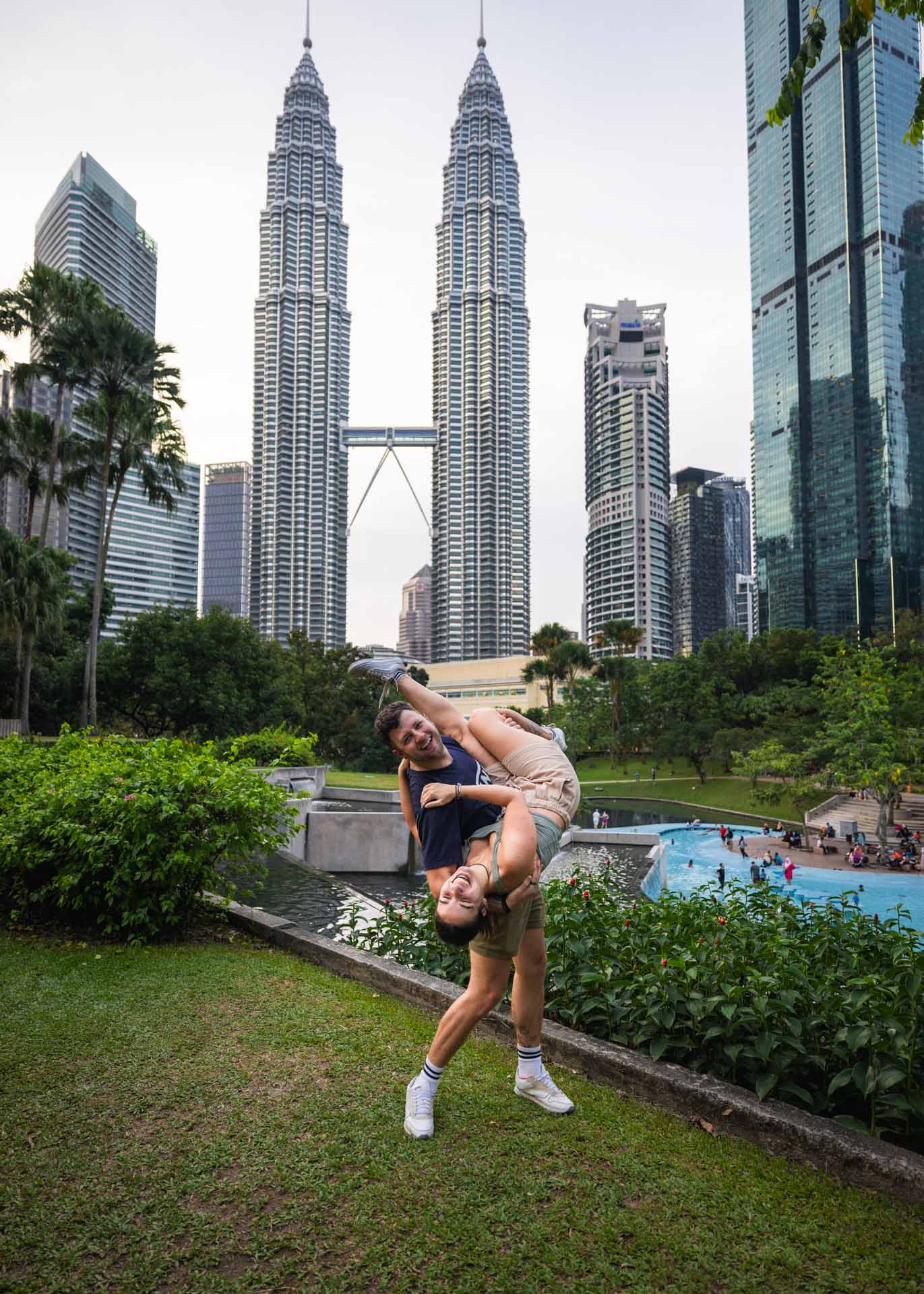Ryan holding Sara upside down while posing in front of the Petronas Towers in Kuala Lumpur.