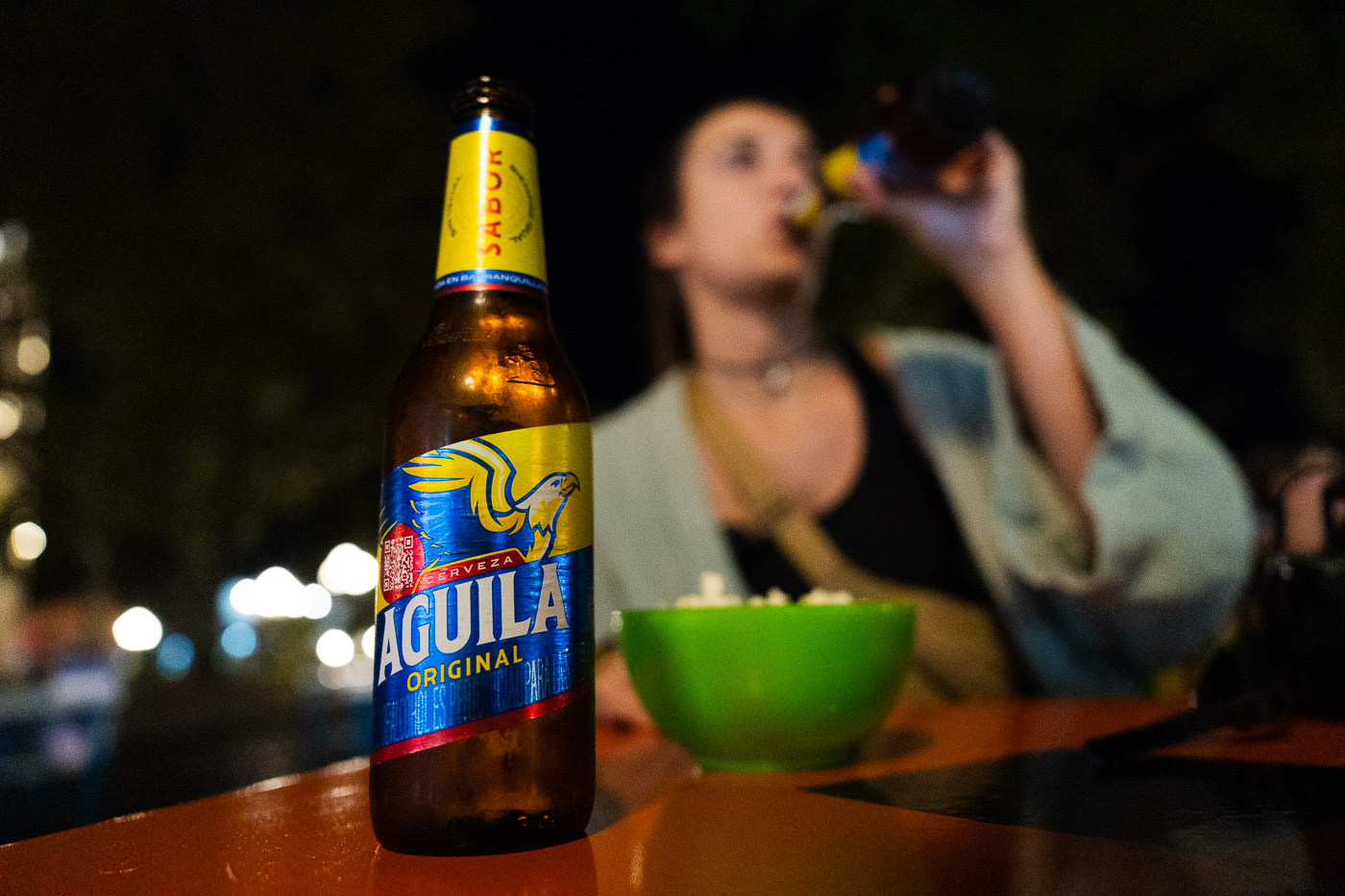 A local Aguila beer bottle while Sara sips from another bottle in the background.