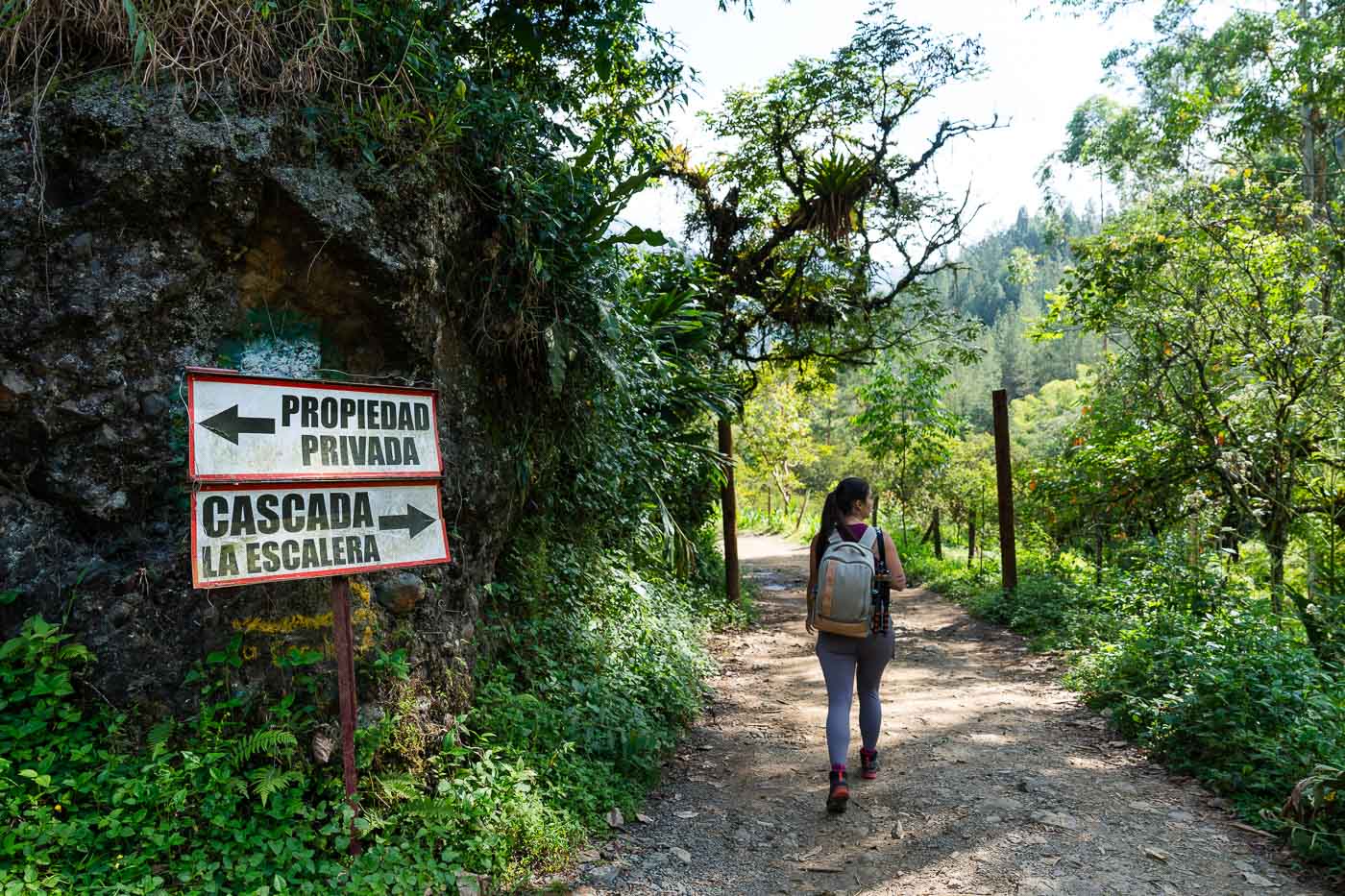 Sara walking down a pathway with the sign for Cascada la Escalera to her left.