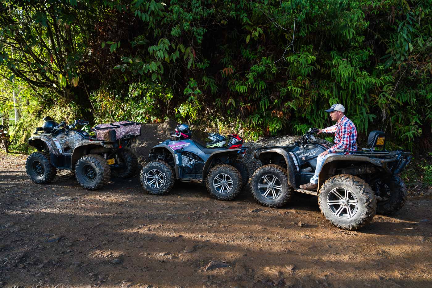 Three ATV bikes lined up in a row with a man sitting on the third one.