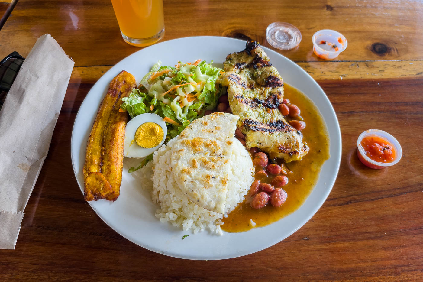 A traditional Colombia Brasa Paisa meal with rice, chicken, plantain, beans and salad.