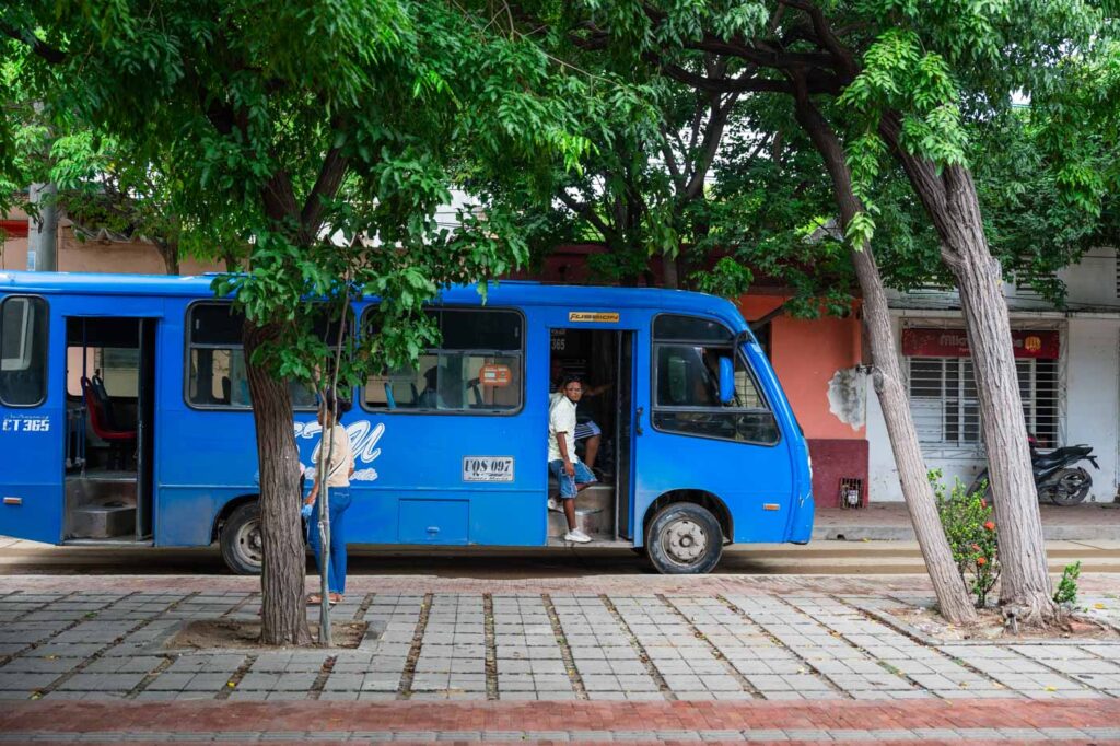 A man standing at the entrance of a blue public bus in Santa Marta.