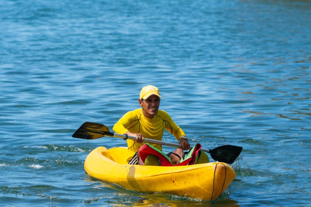 A Colombian man in a yellow kayak on the ocean.