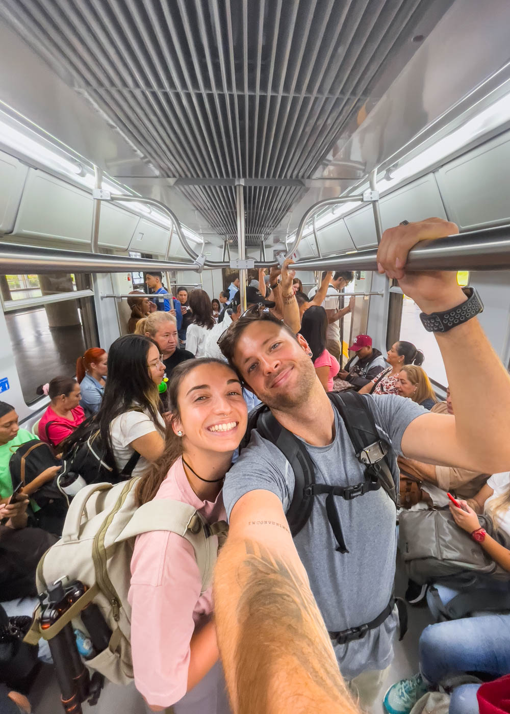 Ryan and Sara taking a selfie inside a busy carriage of the Medellin metro train.