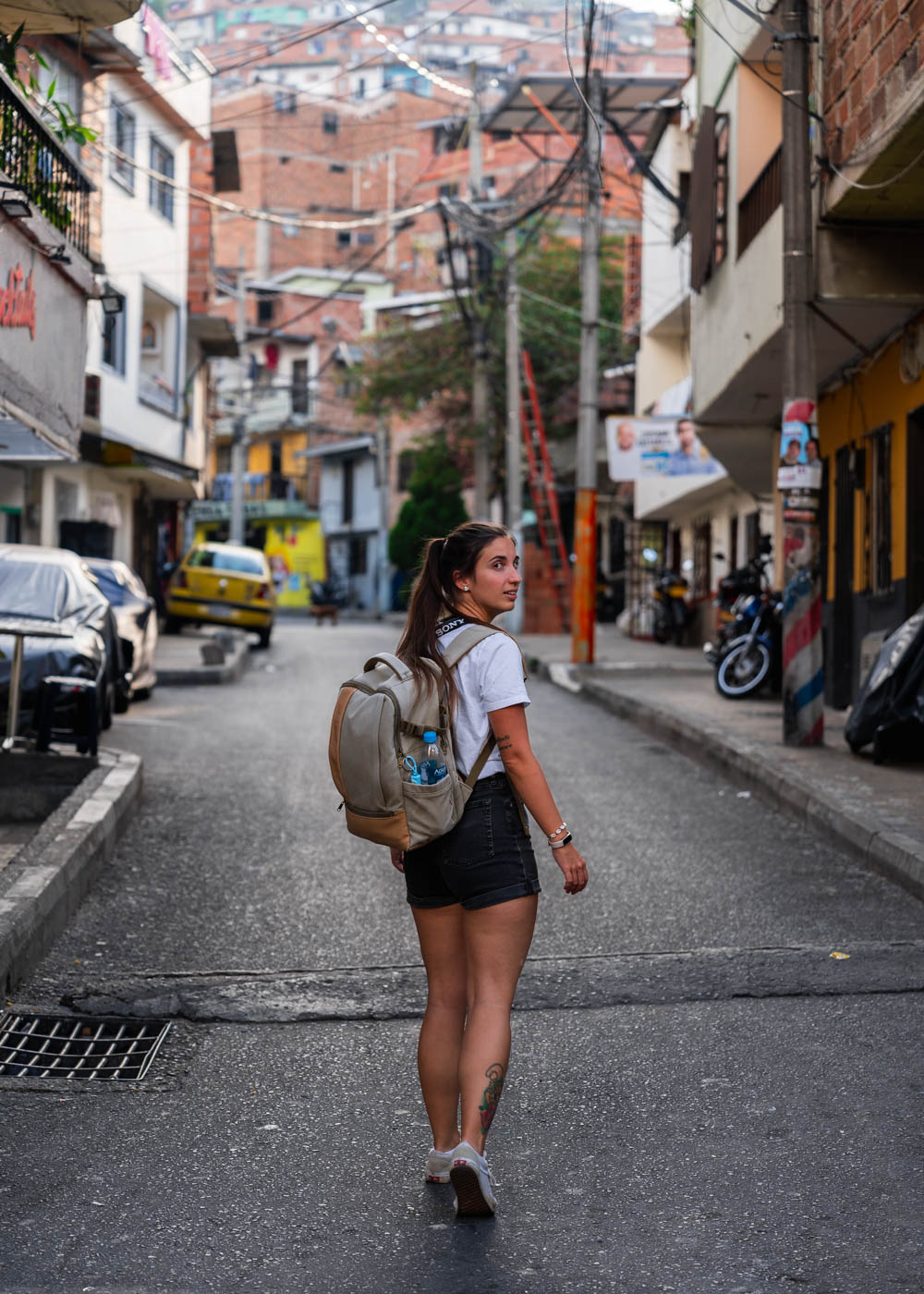 Sara wearing a backpack and walking along a road in Comuna 13.
