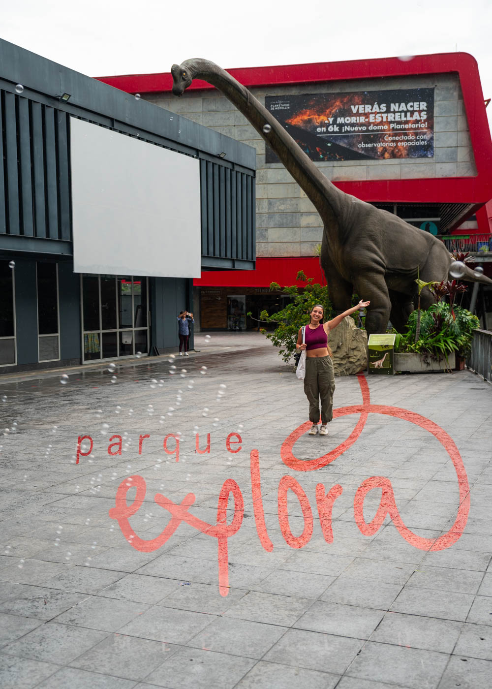 Sara posing besides a giant dinosaur outside the entrance to Parque Explora in Medellin.