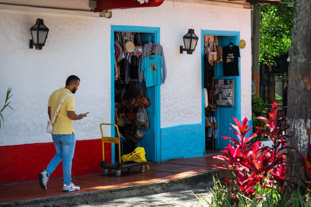 A man walking past store fronts in Pueblito Paisa.