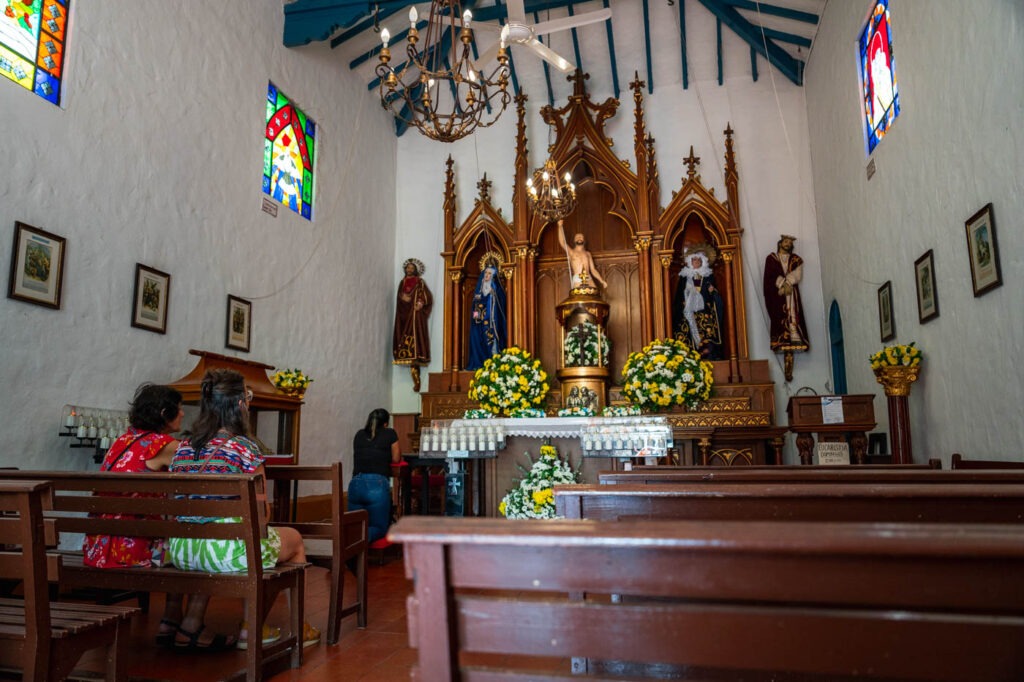 Colombian women sitting inside Pueblito Paisa church praying to the altar.