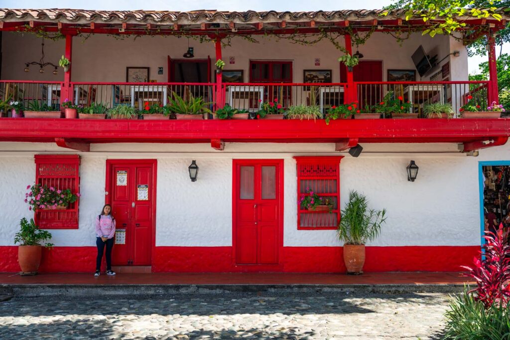 A girl standing outside the colourful restaurant in Pueblito Paisa.