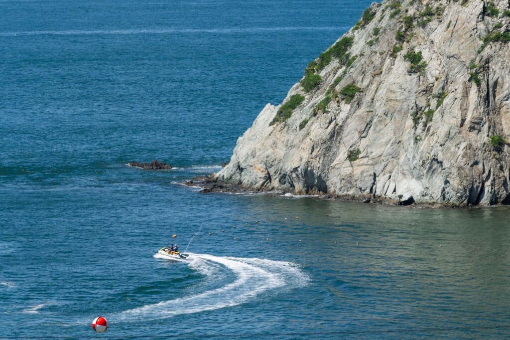 A jet ski making a tight turn besides a cliff.