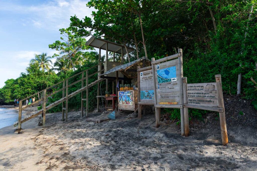 Lifeguard tower, fruit stall and information signs on La Piscina, Tayrona National Park.