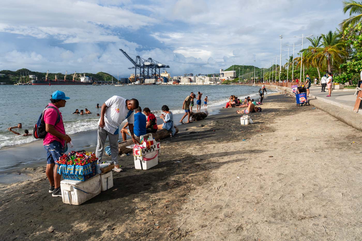 Vendors check their wares on Santa Marta Beach while tourists enjoy their day..