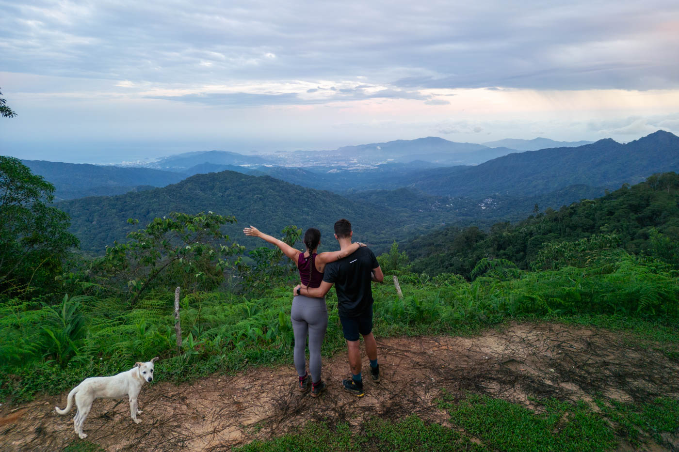 Ryan and Sara hugging at Los Pinos viewpoint overlooking Santa Marta with a white dog.