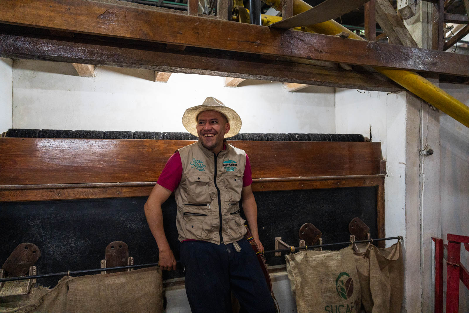 Our tour guide leaning against a factory machine wearing a sombrero and smiling at Finca La Victoria.