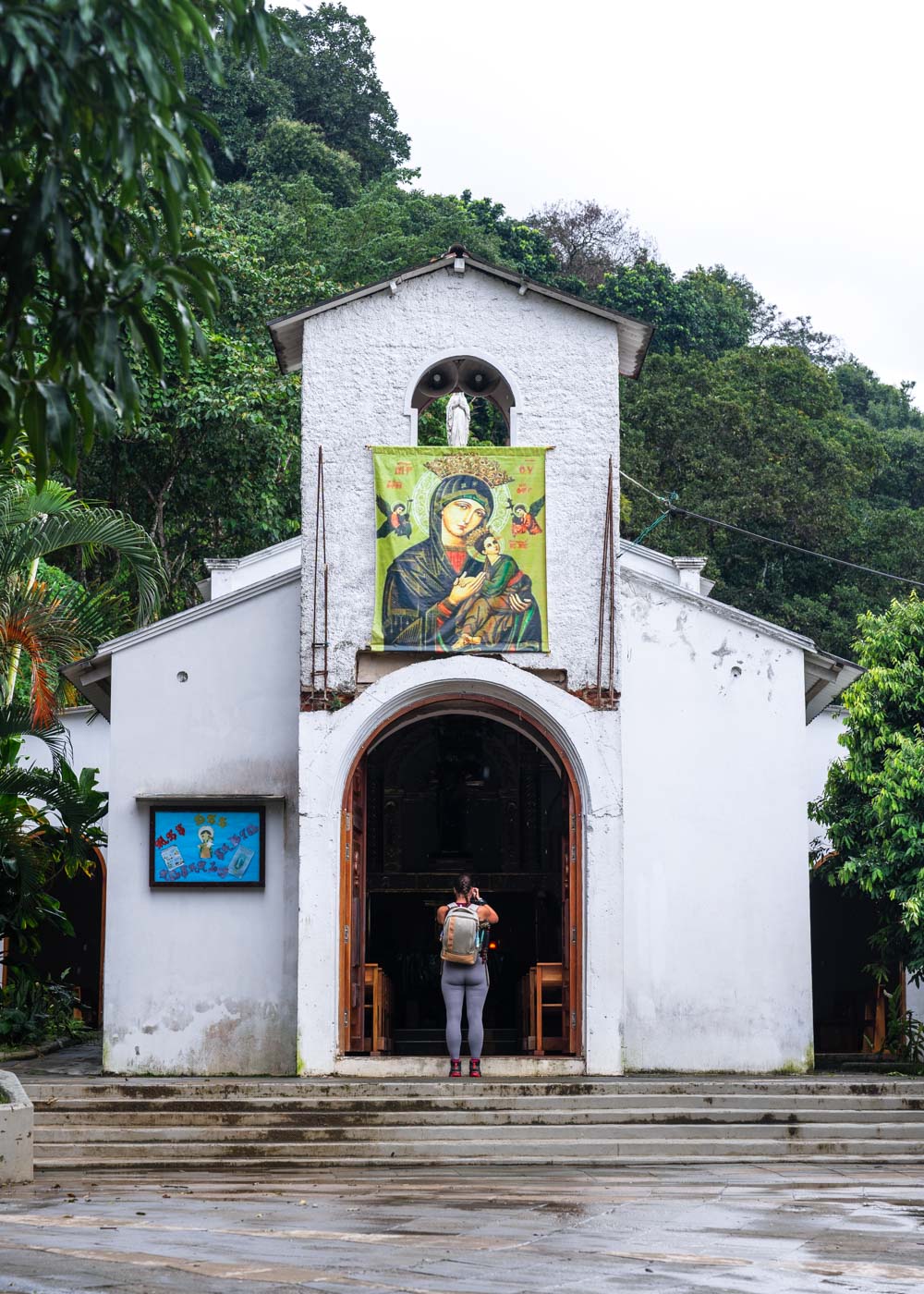 Sara standing in front of the white Church of Minca taking a photo.