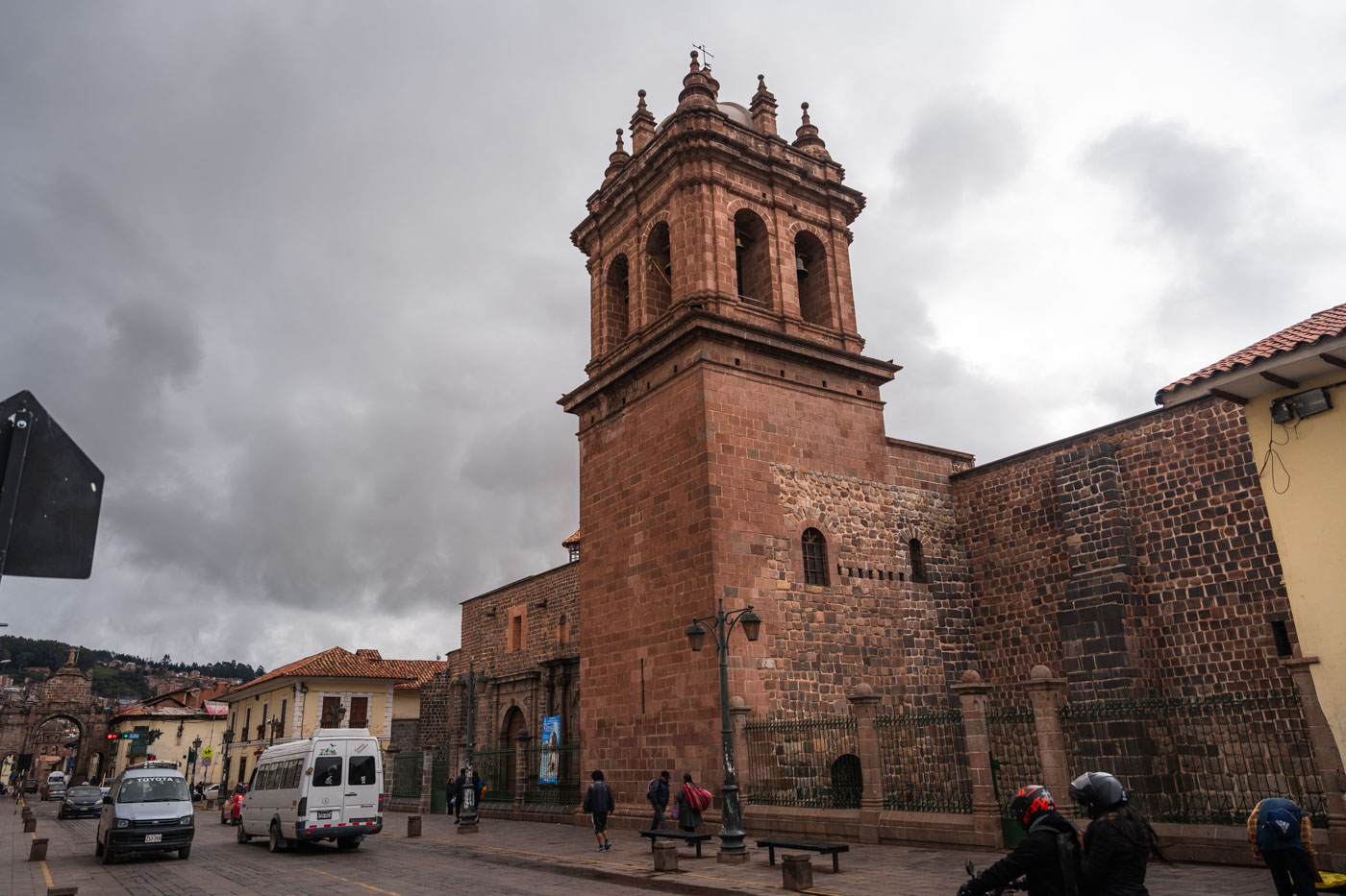 Cars and people passing by Iglesia Convento de Santa Clara in Cusco on an overcast day.
