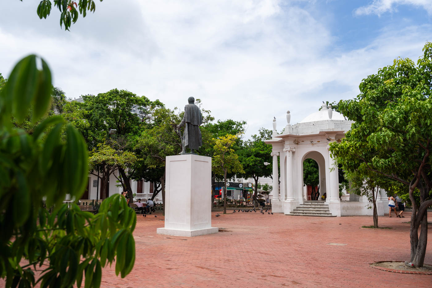Looking across Parque de los Novios to a white, ornate bandstand and a bronze statue of Santander framed by trees.