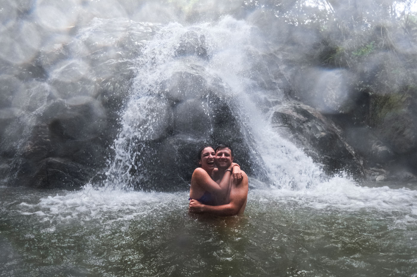 Ryan and Sara hugging tightly while being blasted by the water by the lower Marinka Waterfall.