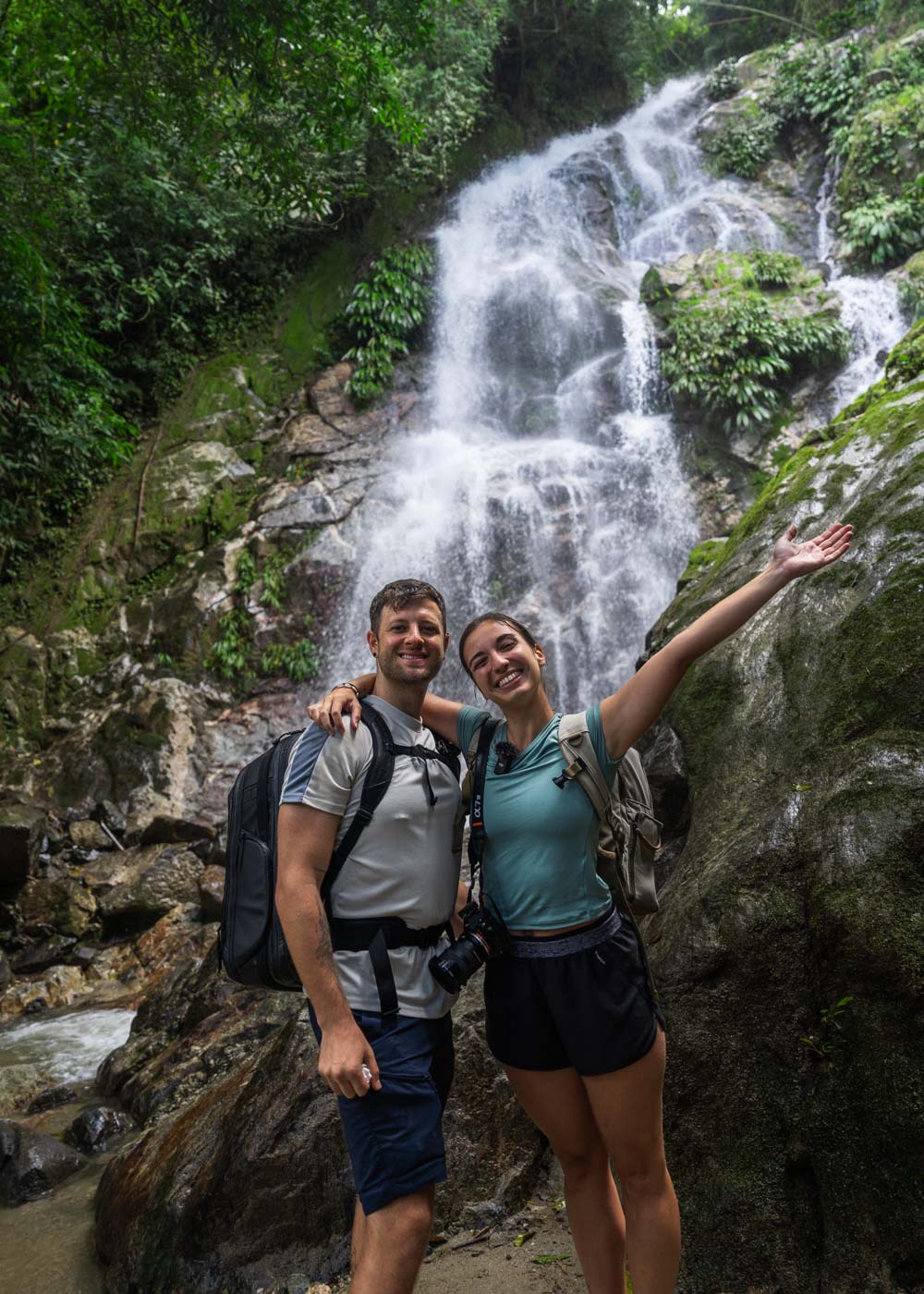 Ryan and Sara in hiking gear with their arms wrapped around each other posing in front of the upper Marinka Waterfall.