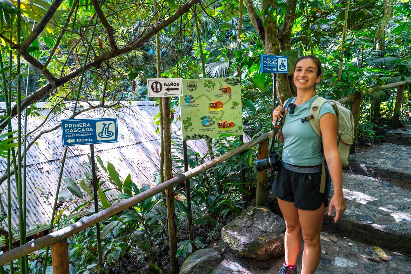Sara standing besides different signs and a map depicting the route around Marinka Waterfalls.