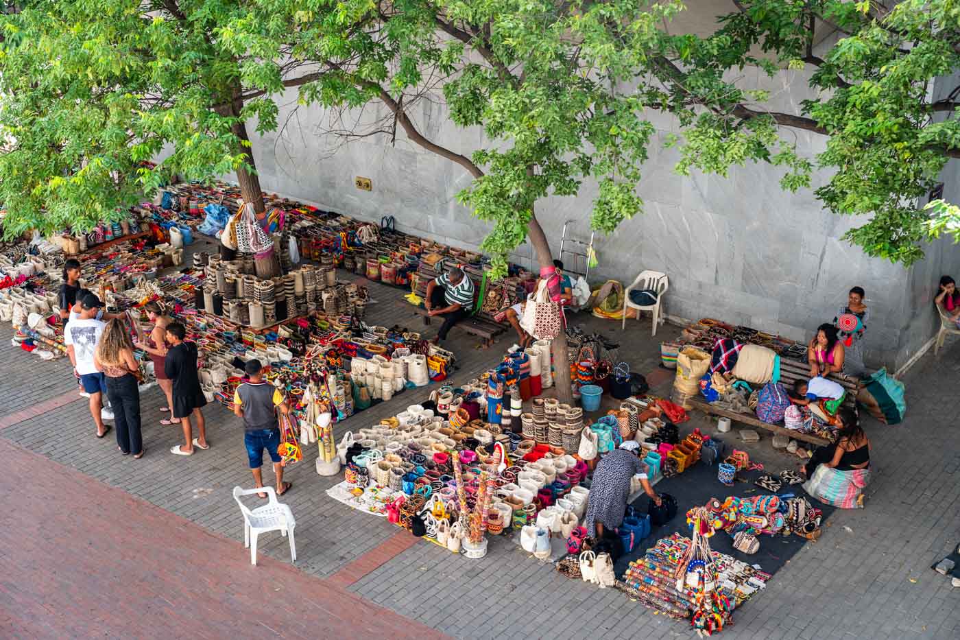 Overlooking a souvenir market with colorful, handmade products covered by green trees in Santa Marta historic center.