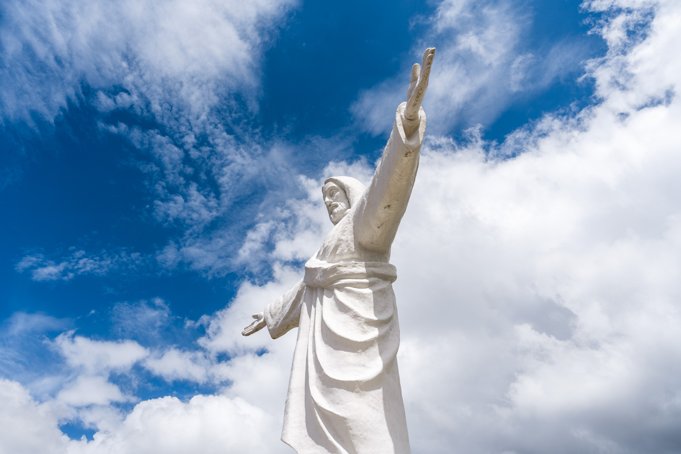 The white Cristo Blanco statue in Cusco with it's arms wide and a backdrop of the sky.