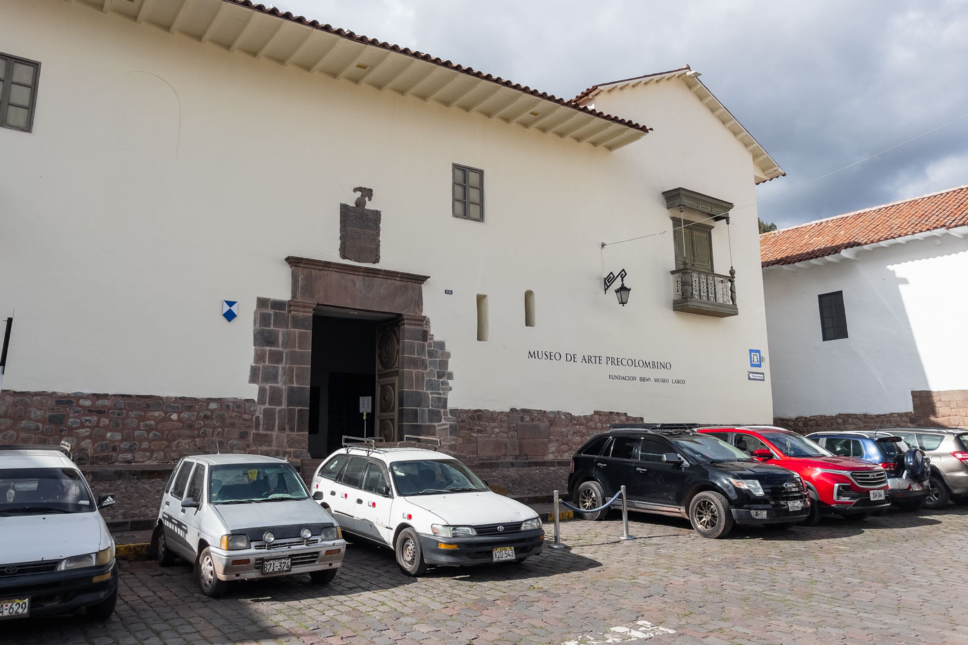 Cars parked outside the front of the Museo de Arte Precolombino in Cusco.