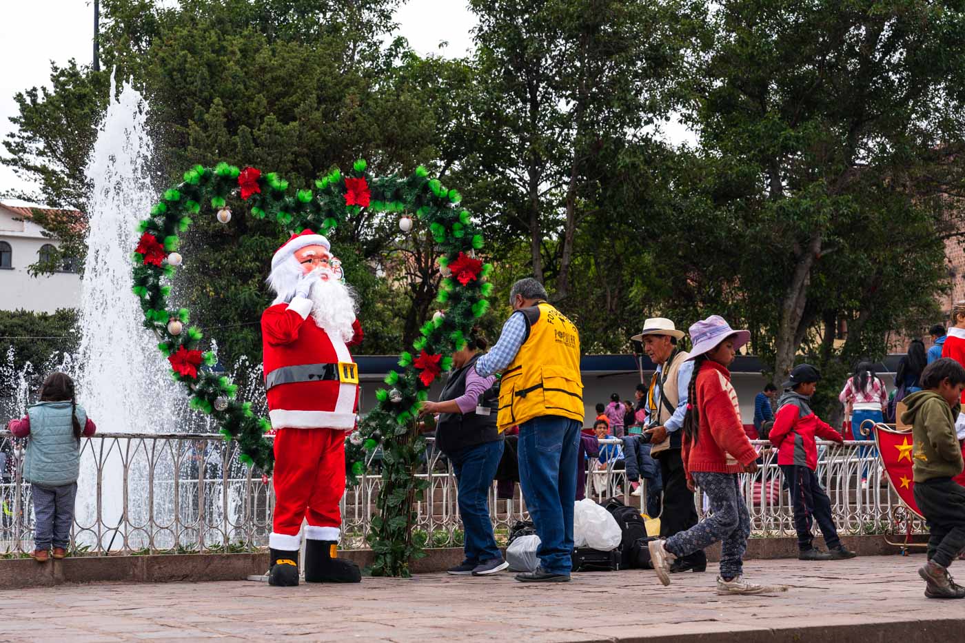 A man dressed as Santa in Plaza San Francisco along with his photographers setting up a display.