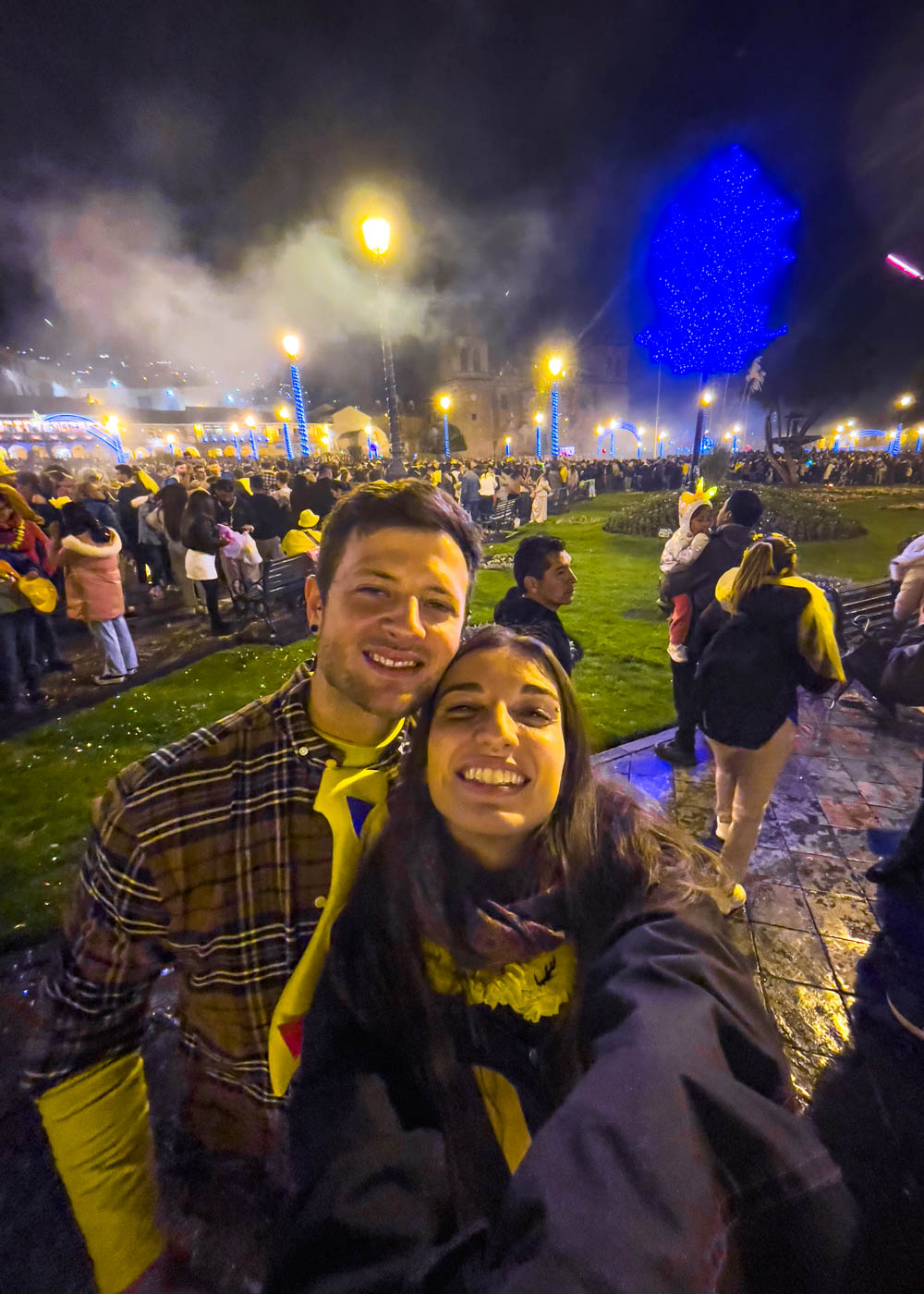 Ryan and Sara taking a selfie in front of crowds at Plaza de Armas while wearing yellow on New Year's Eve in Cusco.
