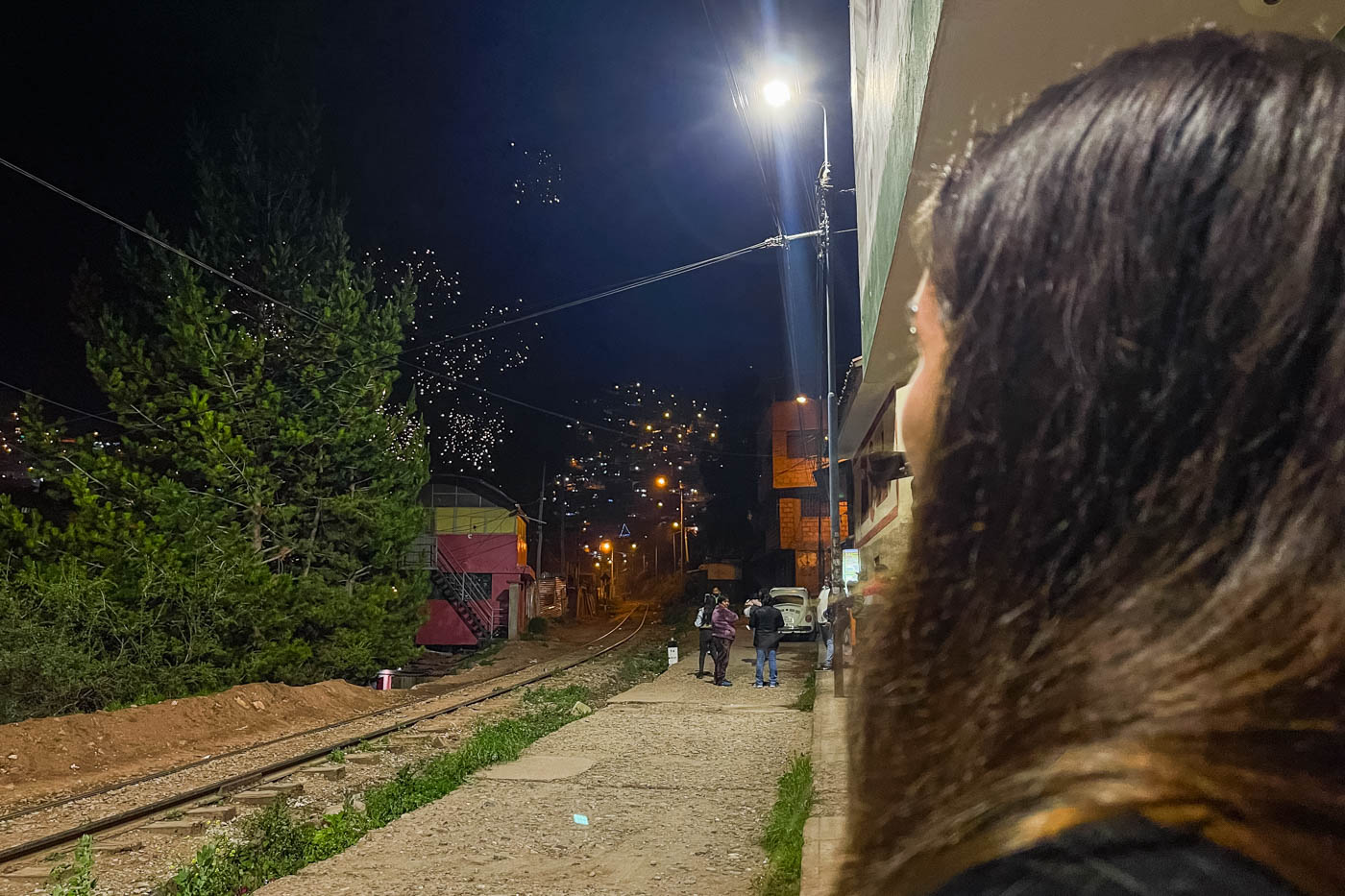 Sara watching fireworks in the distance in Cusco with a view down the train tracks.