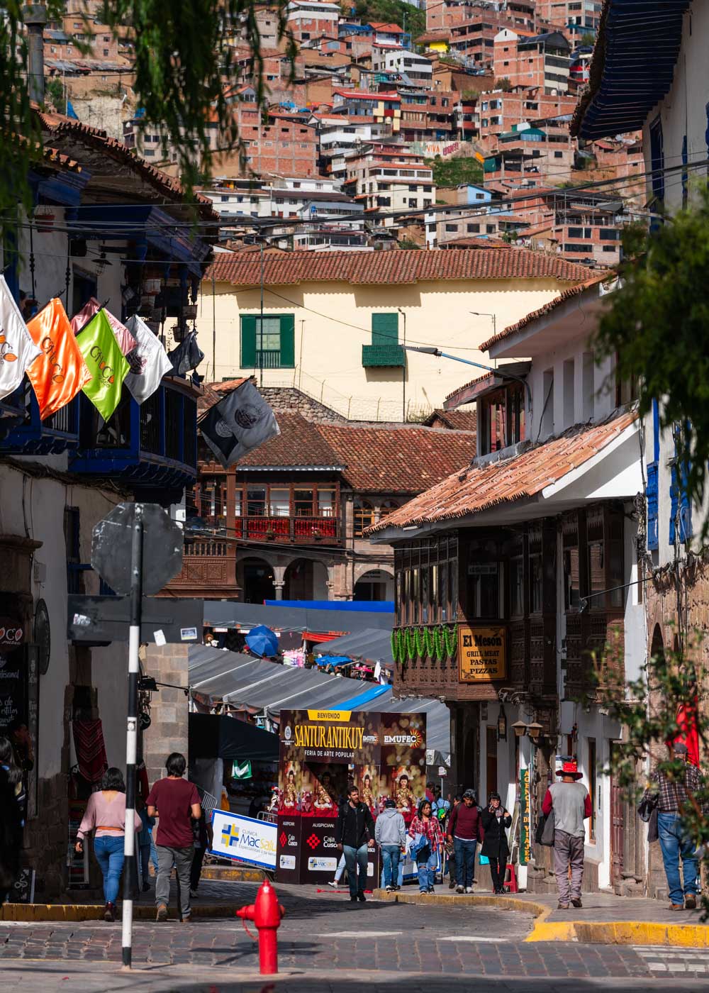 Tourists walking towards Plaza de Armas in Cusco with a markets on the square and a view of favelas in the backgroud.