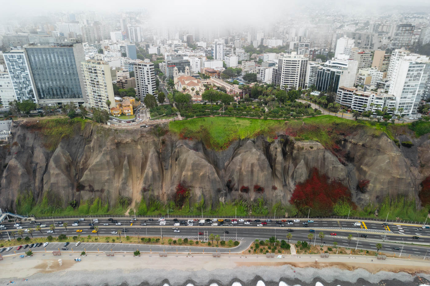 An aerial view of a huge coastline cliff with a large portion of Miraflores built on top in Lima.