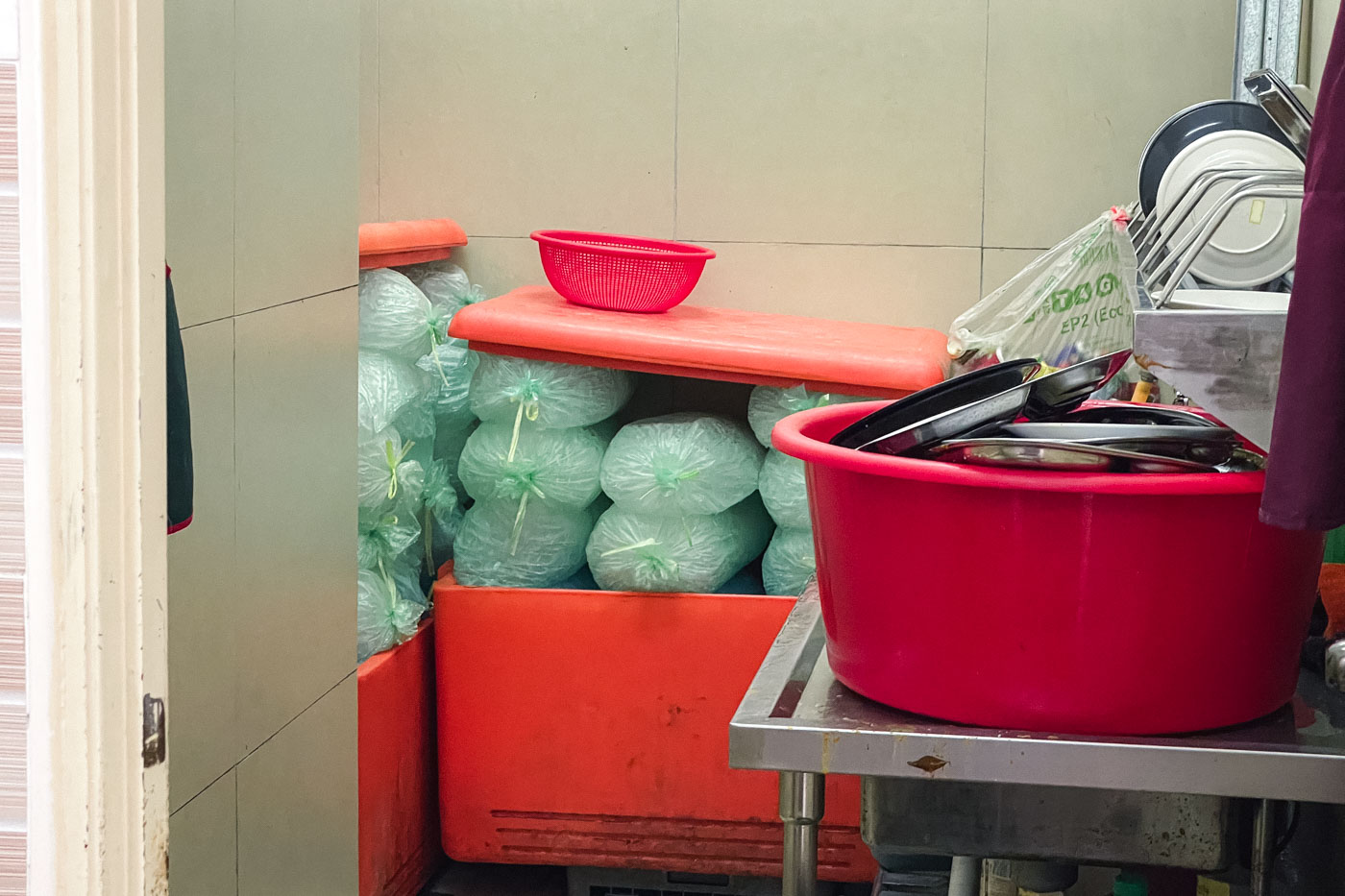 Bags of ice piled up in cool boxes in the back washroom of a restaurant.