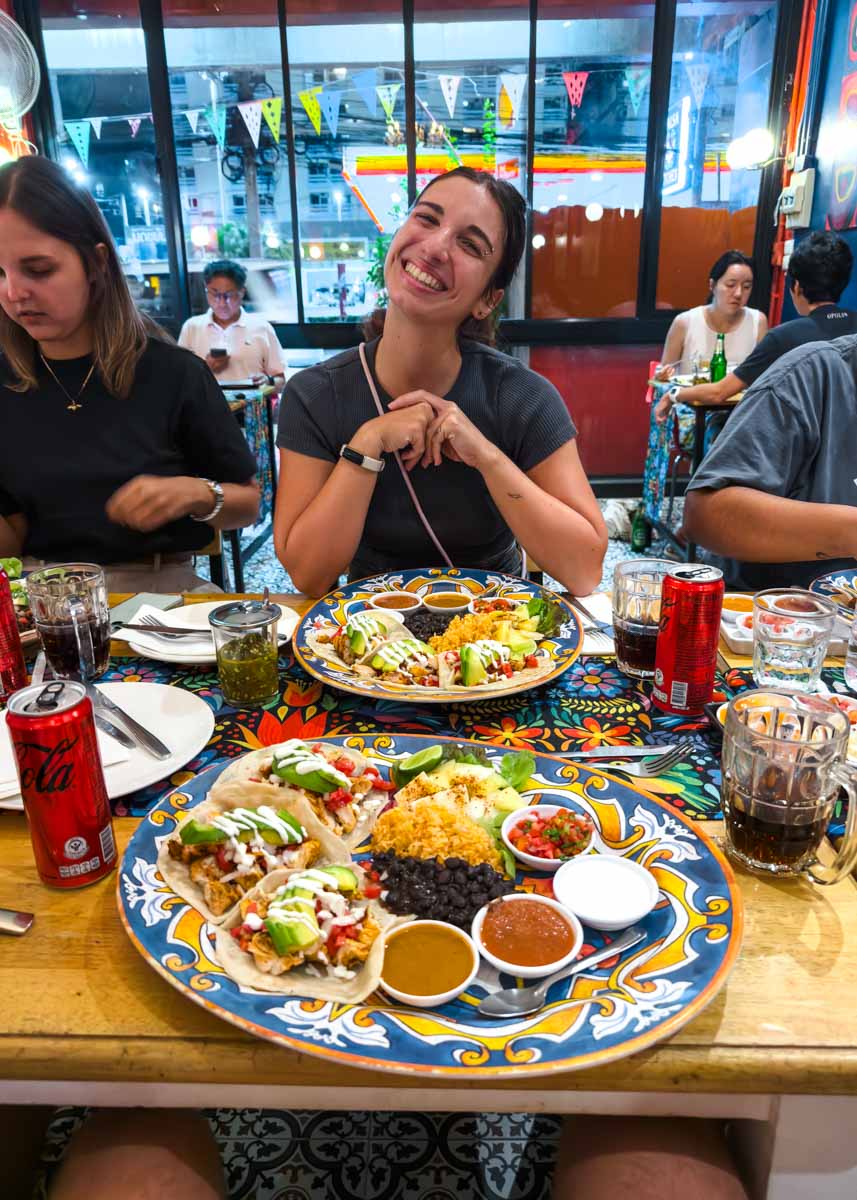 Sara with a big smile with two huge plates of Mexican food on the table in front of her at Salsa Kitchen.