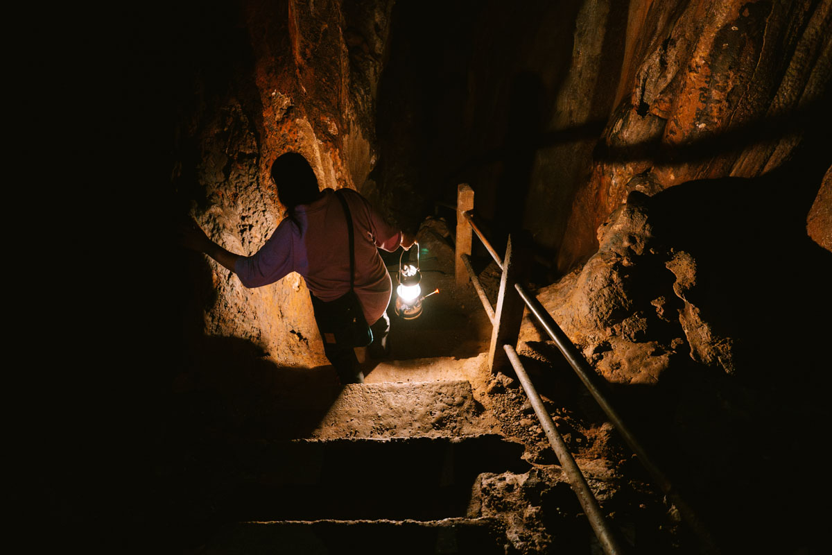 Our guide through Chiang Dao Cave walking down a set of steps and illuminating the surrounding area with her paraffin lamp.