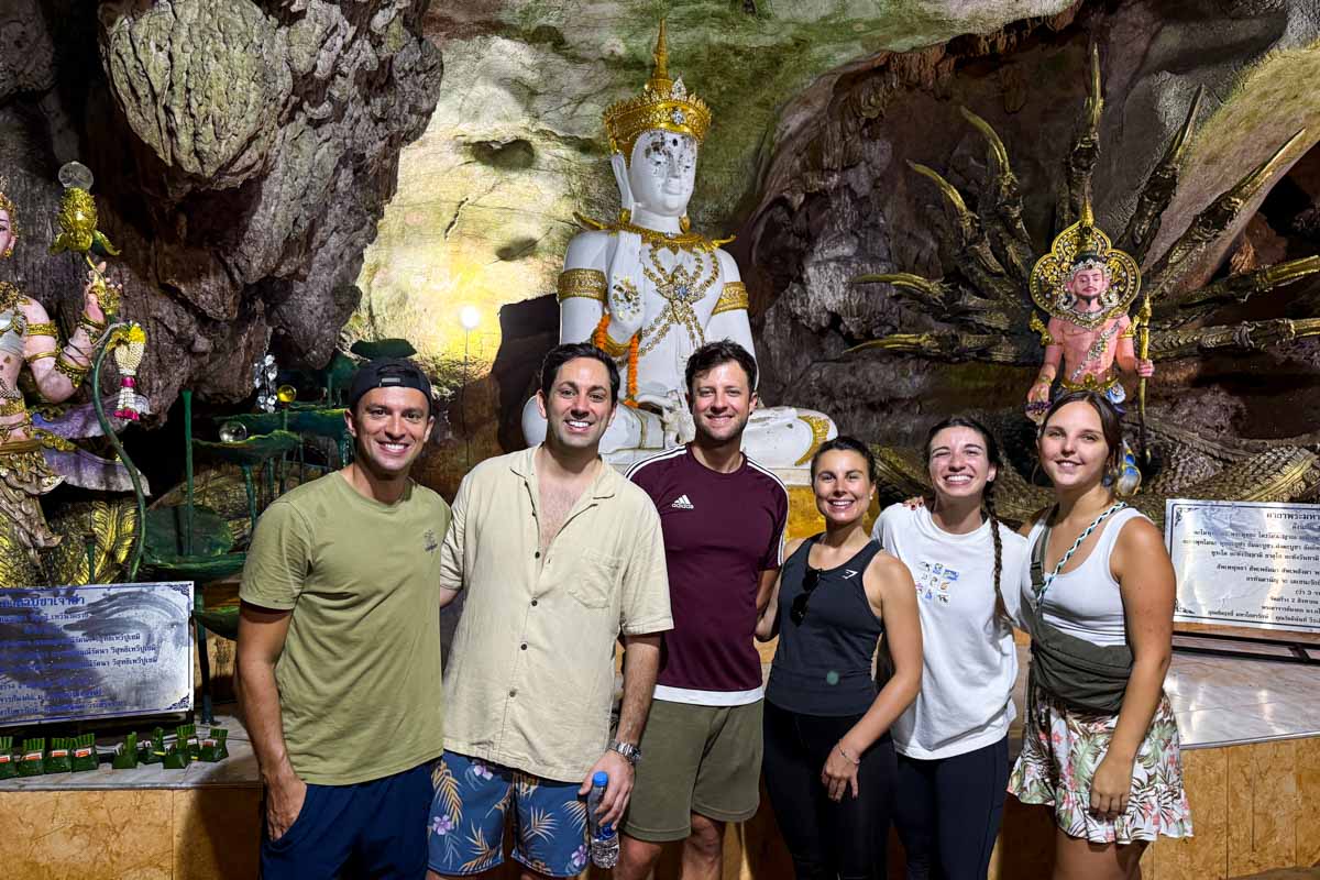 Sara and I lining up with our friends for a group photo in front of a few Buddhist statues inside a cave.